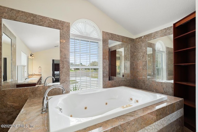 full bathroom with vanity, lofted ceiling, a jetted tub, and tile walls