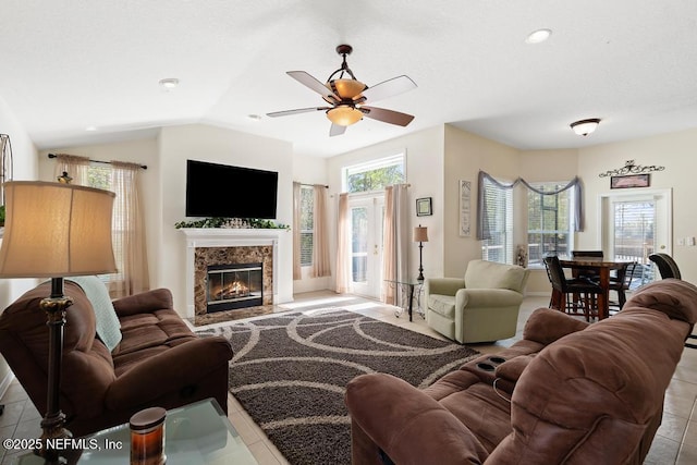 living room featuring tile patterned flooring, lofted ceiling, a fireplace, and a ceiling fan