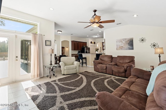 living room featuring light tile patterned floors, visible vents, recessed lighting, arched walkways, and vaulted ceiling