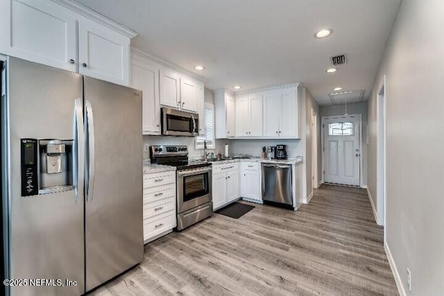 kitchen featuring baseboards, stainless steel appliances, light countertops, white cabinets, and light wood-style floors