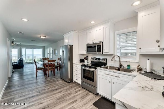 kitchen with white cabinets, light wood finished floors, appliances with stainless steel finishes, and a sink