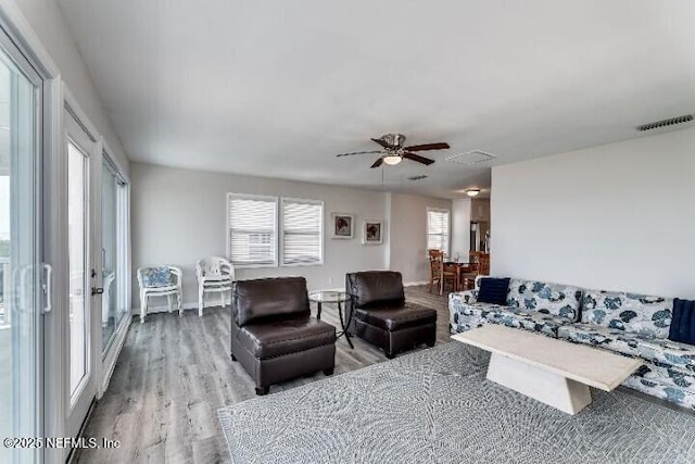 living area with visible vents, baseboards, wood finished floors, and a ceiling fan