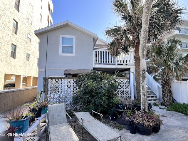 exterior space featuring stairway, fence, and stucco siding