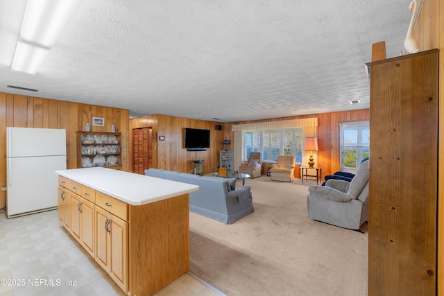 living area with light carpet, light floors, wooden walls, and a textured ceiling