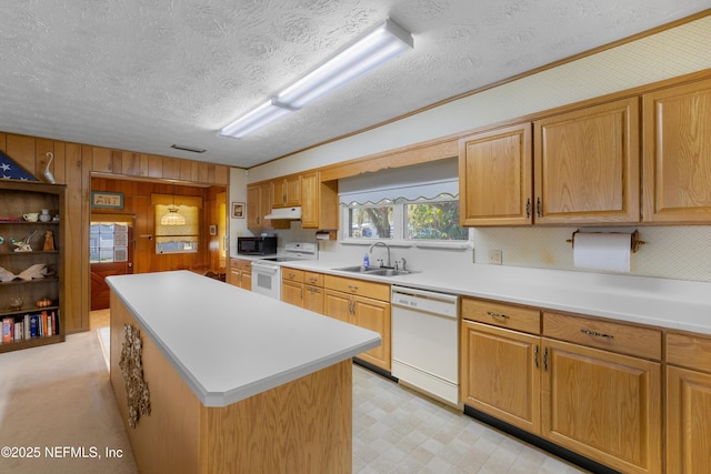 kitchen with white appliances, light floors, a sink, light countertops, and a center island