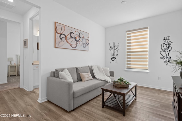 living room with visible vents, light wood-style flooring, and baseboards