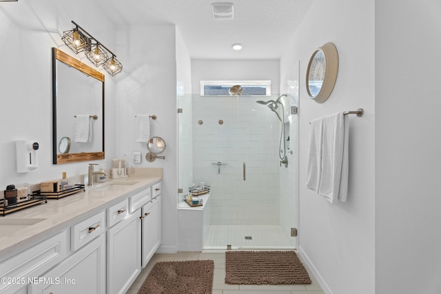 bathroom featuring tile patterned flooring, double vanity, a stall shower, a textured ceiling, and a sink