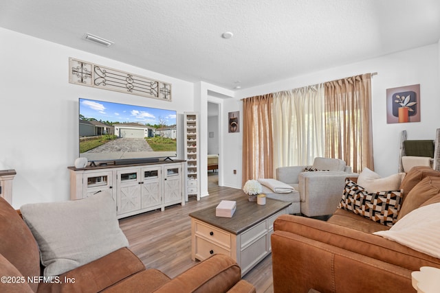 living room featuring visible vents, a textured ceiling, light wood-type flooring, and built in features