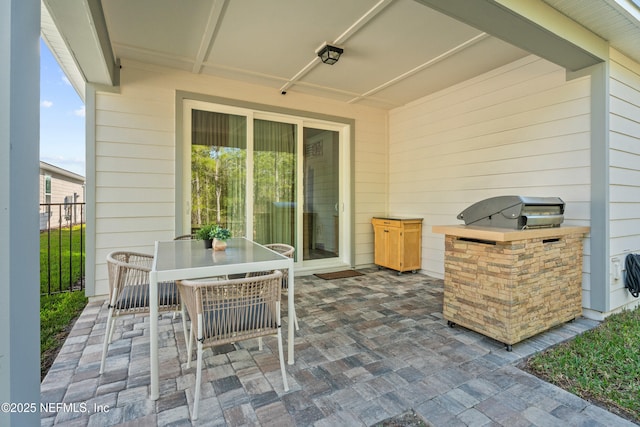 view of patio featuring exterior kitchen, outdoor dining area, and fence