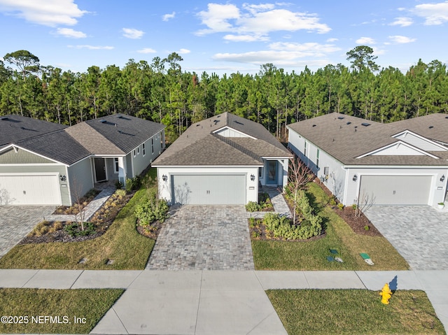 view of front of property featuring a front yard, decorative driveway, a garage, and a shingled roof