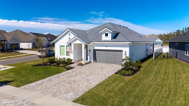 view of front of house with a shingled roof, driveway, a front lawn, and an attached garage
