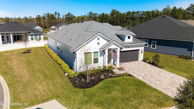 view of front facade featuring driveway, an attached garage, fence, a front lawn, and a shingled roof