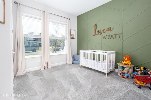 bedroom featuring baseboards, a crib, and carpet