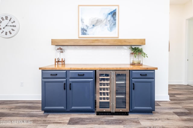 bar with baseboards, a dry bar, wood finished floors, and beverage cooler