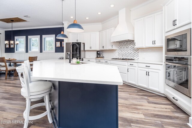 kitchen with stainless steel gas stovetop, a breakfast bar, a sink, custom range hood, and built in microwave