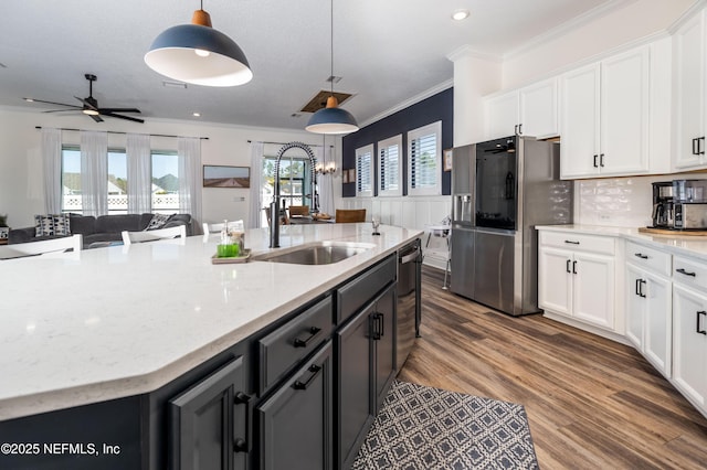 kitchen featuring white cabinets, ornamental molding, wood finished floors, appliances with stainless steel finishes, and a sink