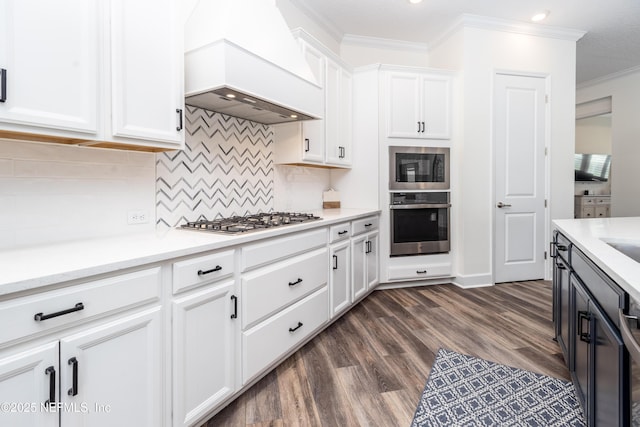 kitchen with white cabinets, light countertops, crown molding, appliances with stainless steel finishes, and custom range hood