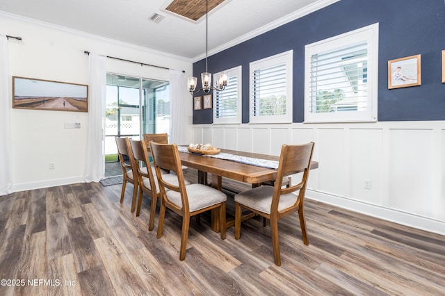 dining space with ornamental molding, visible vents, a chandelier, and wood finished floors