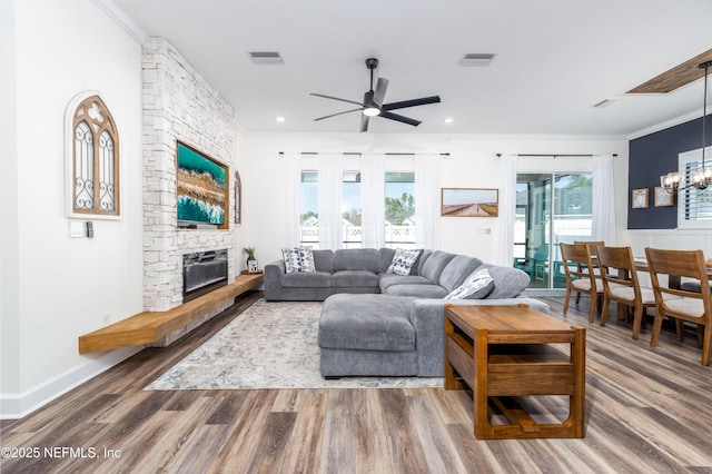 living room featuring ornamental molding, visible vents, and ceiling fan with notable chandelier