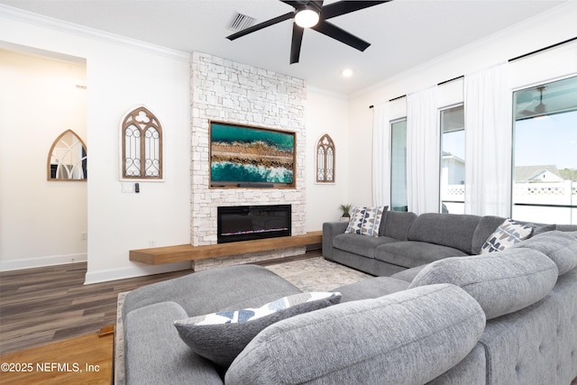 living area with ornamental molding, baseboards, a ceiling fan, a fireplace, and wood finished floors