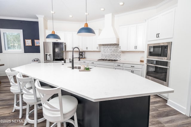 kitchen with custom range hood, ornamental molding, a sink, a large island, and appliances with stainless steel finishes