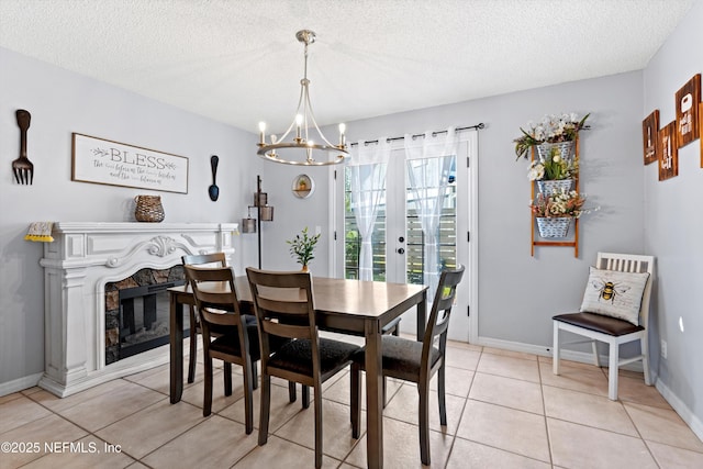 dining area with a textured ceiling, a high end fireplace, an inviting chandelier, light tile patterned flooring, and baseboards