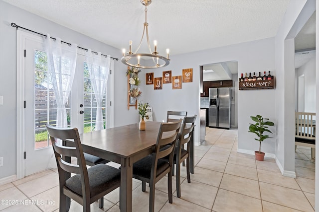 dining area featuring light tile patterned floors, plenty of natural light, a textured ceiling, and a chandelier