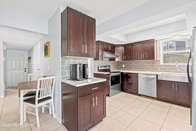 kitchen featuring a sink, tasteful backsplash, under cabinet range hood, and stainless steel appliances