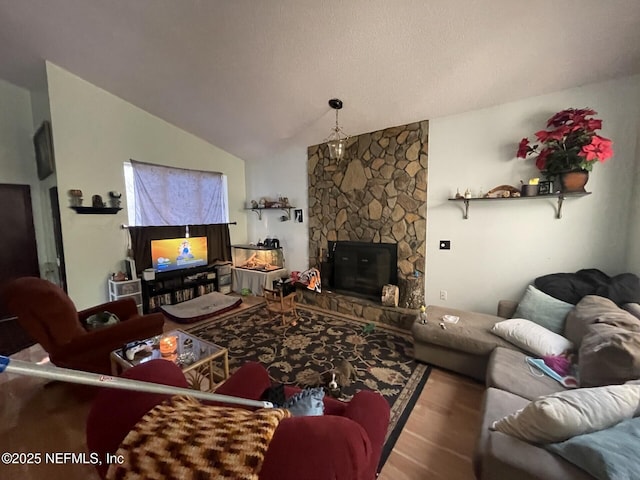 living area with wood finished floors, a fireplace, and vaulted ceiling