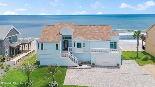 view of front of home with decorative driveway, an attached garage, a water view, and stairs