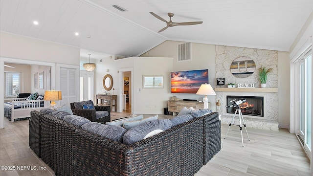 living area with vaulted ceiling, visible vents, a wealth of natural light, and ceiling fan