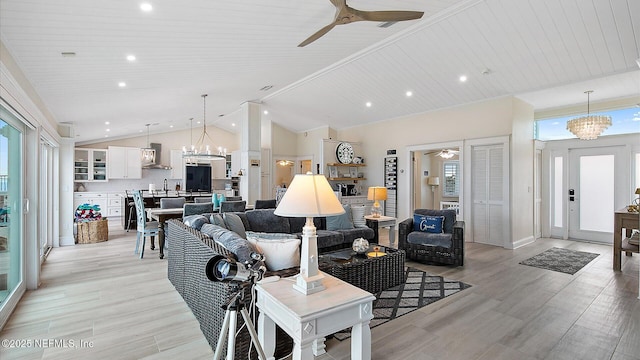 living area featuring recessed lighting, light wood-style flooring, vaulted ceiling, and ceiling fan with notable chandelier