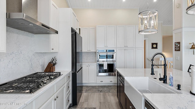 kitchen with a sink, wall chimney range hood, backsplash, and stainless steel appliances