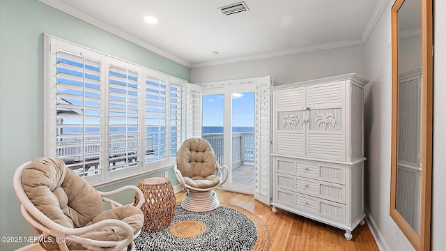 sitting room featuring visible vents, baseboards, crown molding, and light wood-style floors