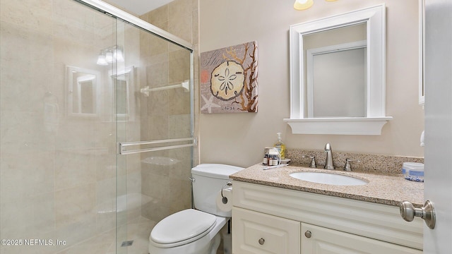 bathroom with toilet, a stall shower, and vanity