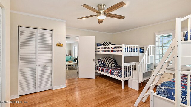 bedroom featuring wood finished floors, baseboards, ceiling fan, ornamental molding, and a closet