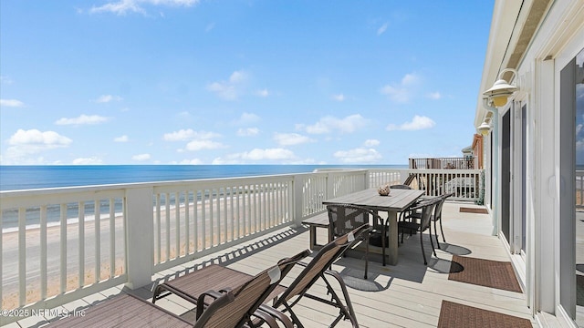 deck featuring outdoor dining area, a view of the beach, and a water view