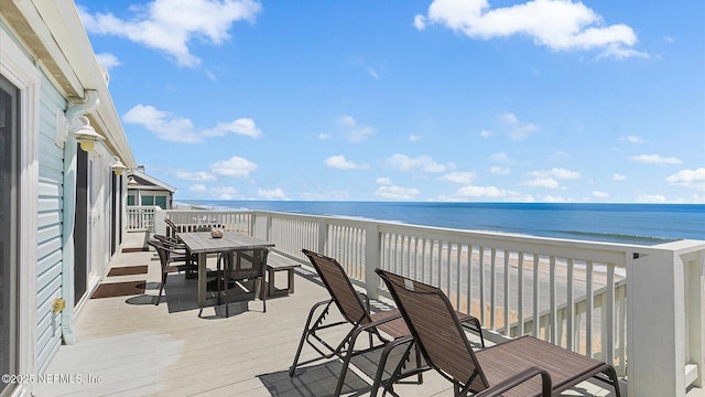 balcony featuring outdoor dining space, a view of the beach, and a deck with water view