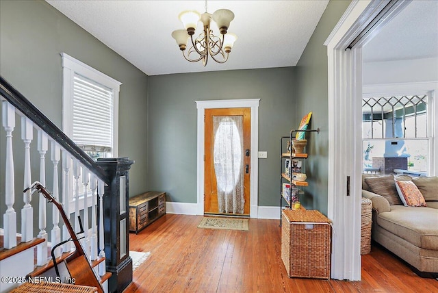 entrance foyer featuring plenty of natural light, an inviting chandelier, stairs, and light wood finished floors