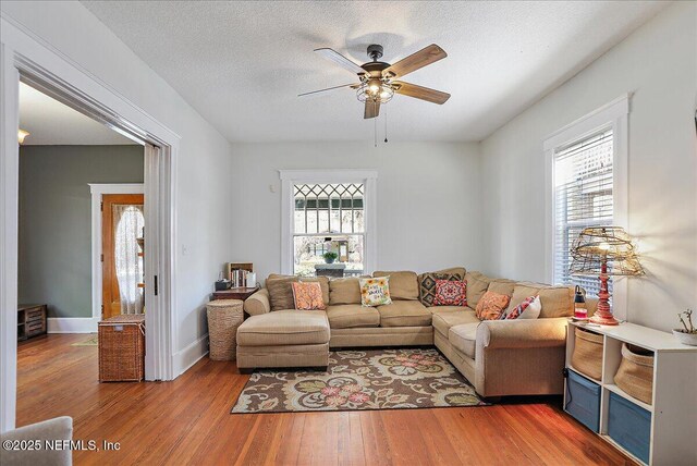 living area with a wealth of natural light, a textured ceiling, ceiling fan, and wood finished floors