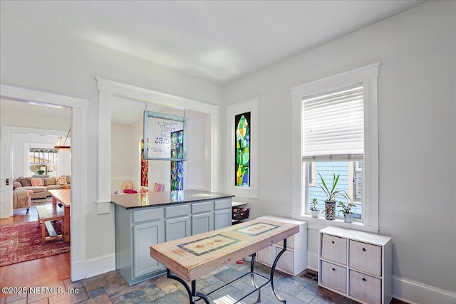 office with a wealth of natural light, baseboards, and stone tile floors