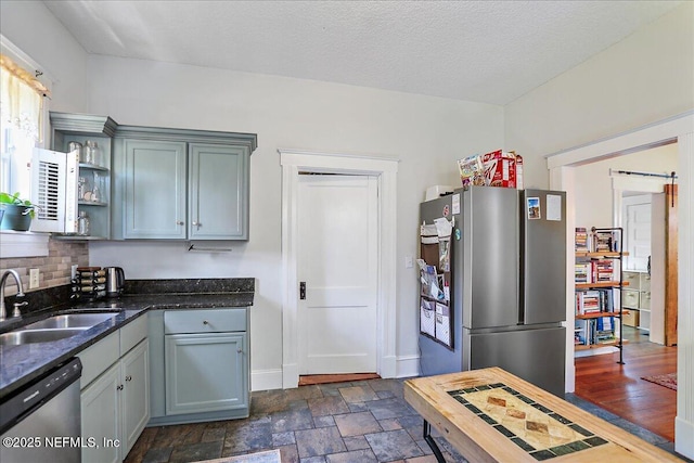 kitchen with a sink, open shelves, stone finish flooring, tasteful backsplash, and appliances with stainless steel finishes