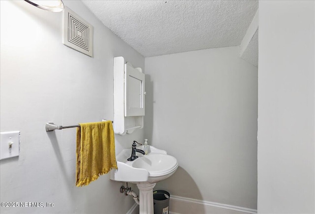 bathroom with visible vents, a textured ceiling, and a sink