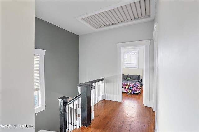 corridor with hardwood / wood-style floors, an upstairs landing, and visible vents