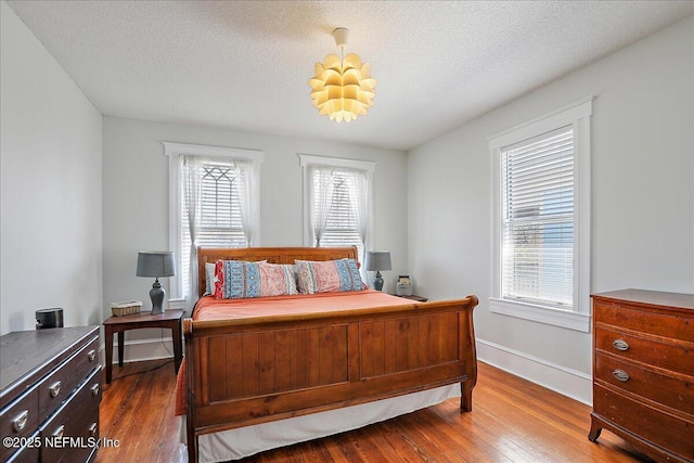 bedroom with dark wood finished floors, a textured ceiling, and baseboards