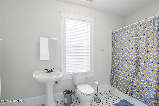 bathroom with baseboards, tile patterned floors, toilet, and a shower with curtain