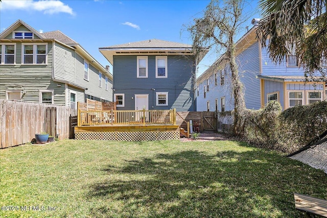 back of property with a yard, a deck, and a fenced backyard