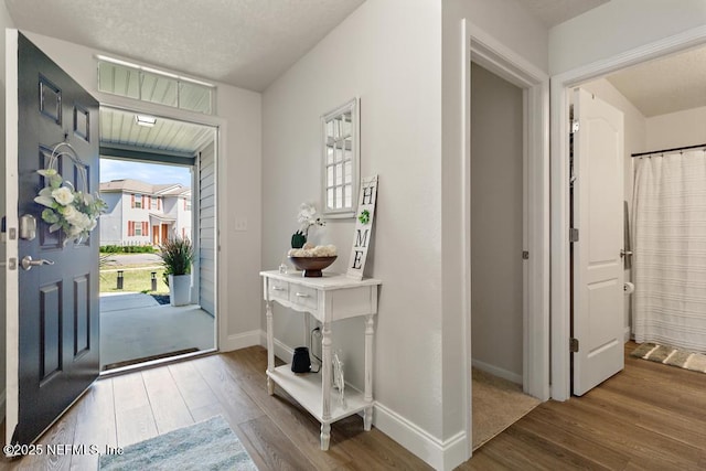 entrance foyer with a textured ceiling, baseboards, and wood finished floors