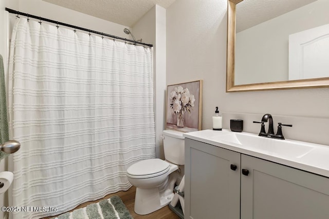 full bathroom featuring a textured ceiling, wood finished floors, vanity, and toilet