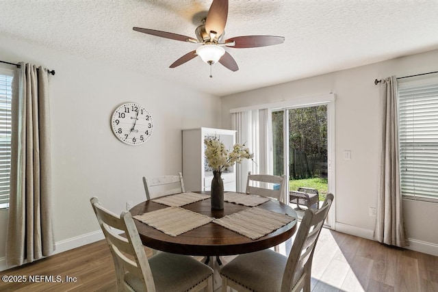 dining space with baseboards, a textured ceiling, a ceiling fan, and light wood finished floors